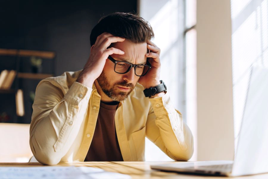 Man with headache behind computer